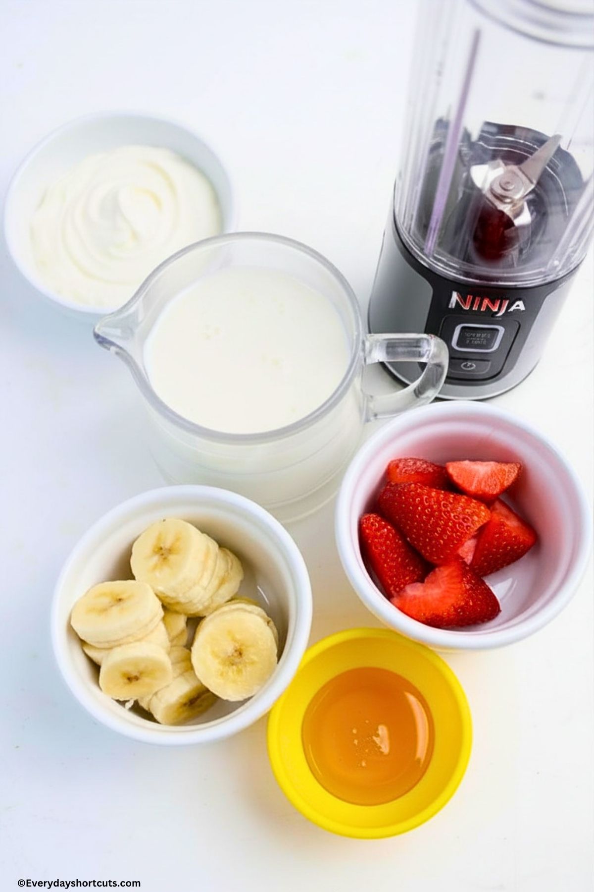 ingredients shown: Greek yogurt, milk, banana, strawberries, honey, blender