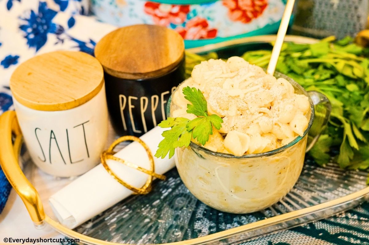 Copycat Panera White Mac and Cheese in a cup bowl with a spoon on a platter with salt and pepper shaker