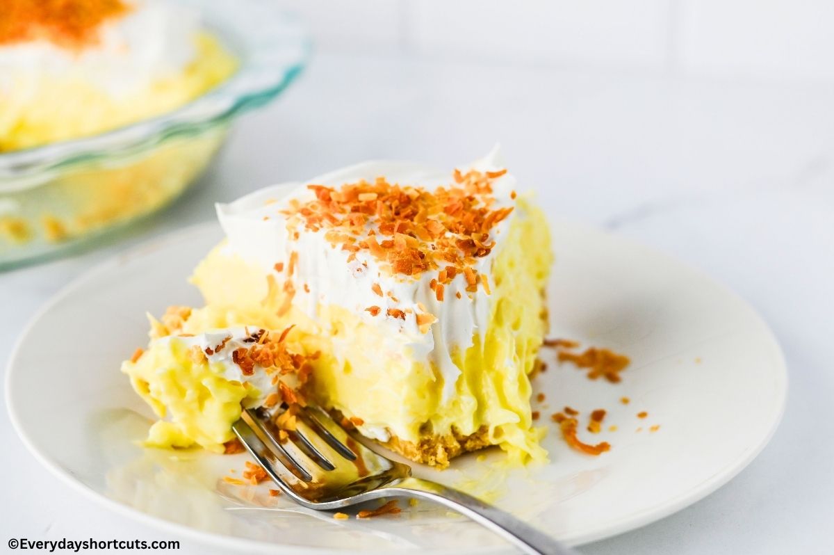 A piece taken off and on a fork next to a slice of coconut cream pie on a white plate