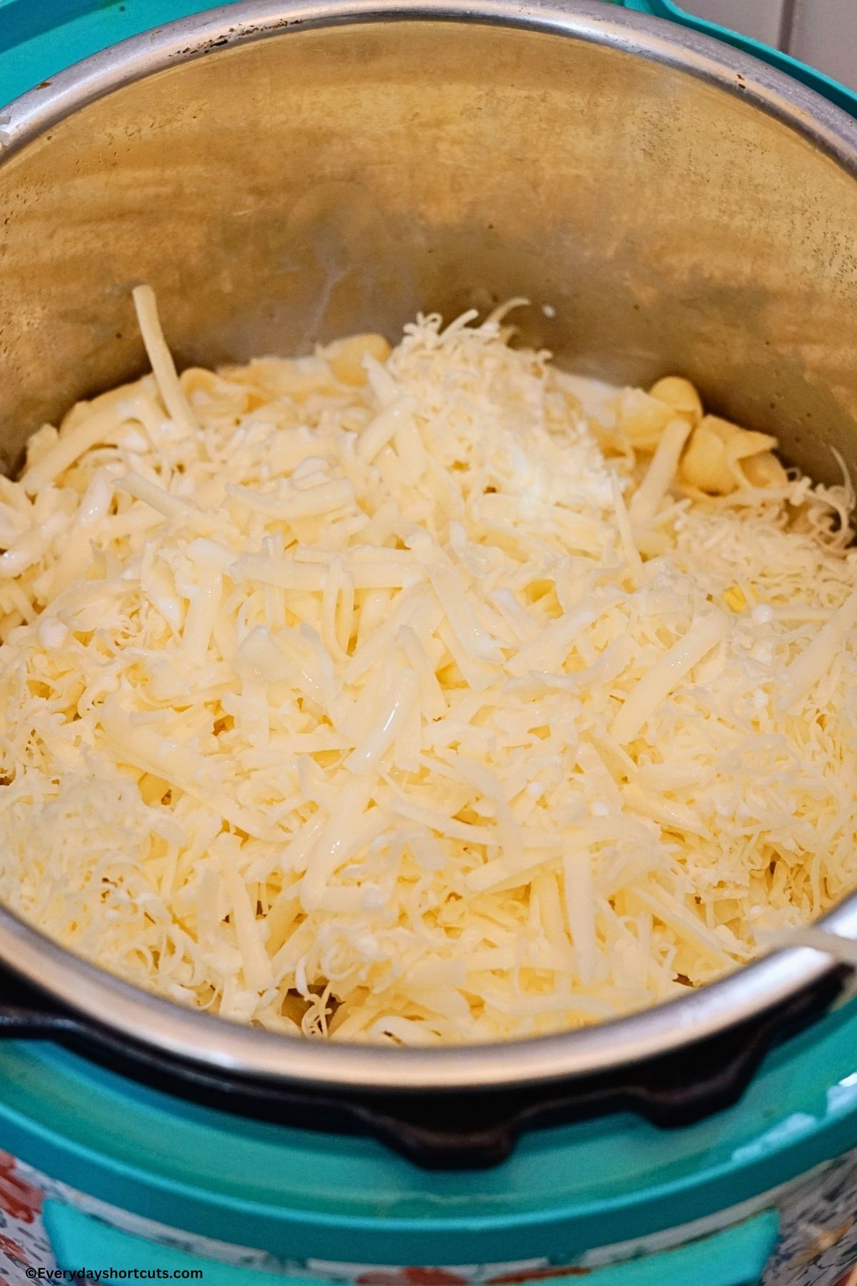 milk, white cheddar cheese, white American cheddar cheese in an Instant Pot with cooked pasta shells