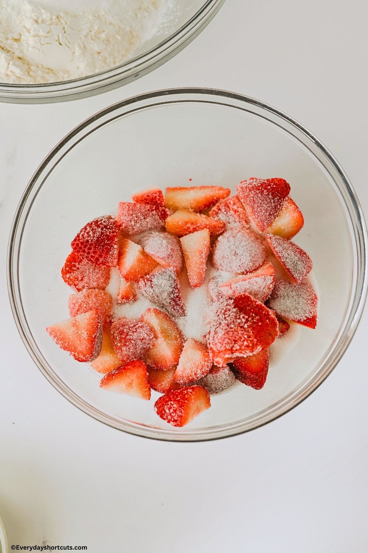 halved strawberries in a bowl with sugar