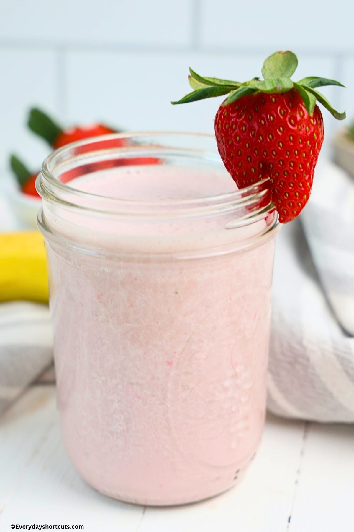 glass of strawberry banana smoothie with a strawberry garnish