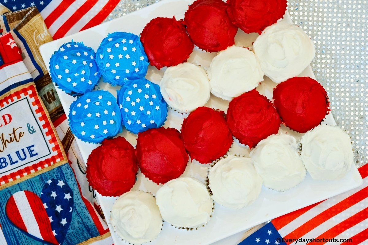 frosting cupcakes in the shape of an American flag and frosted with red white and blue on a white platter