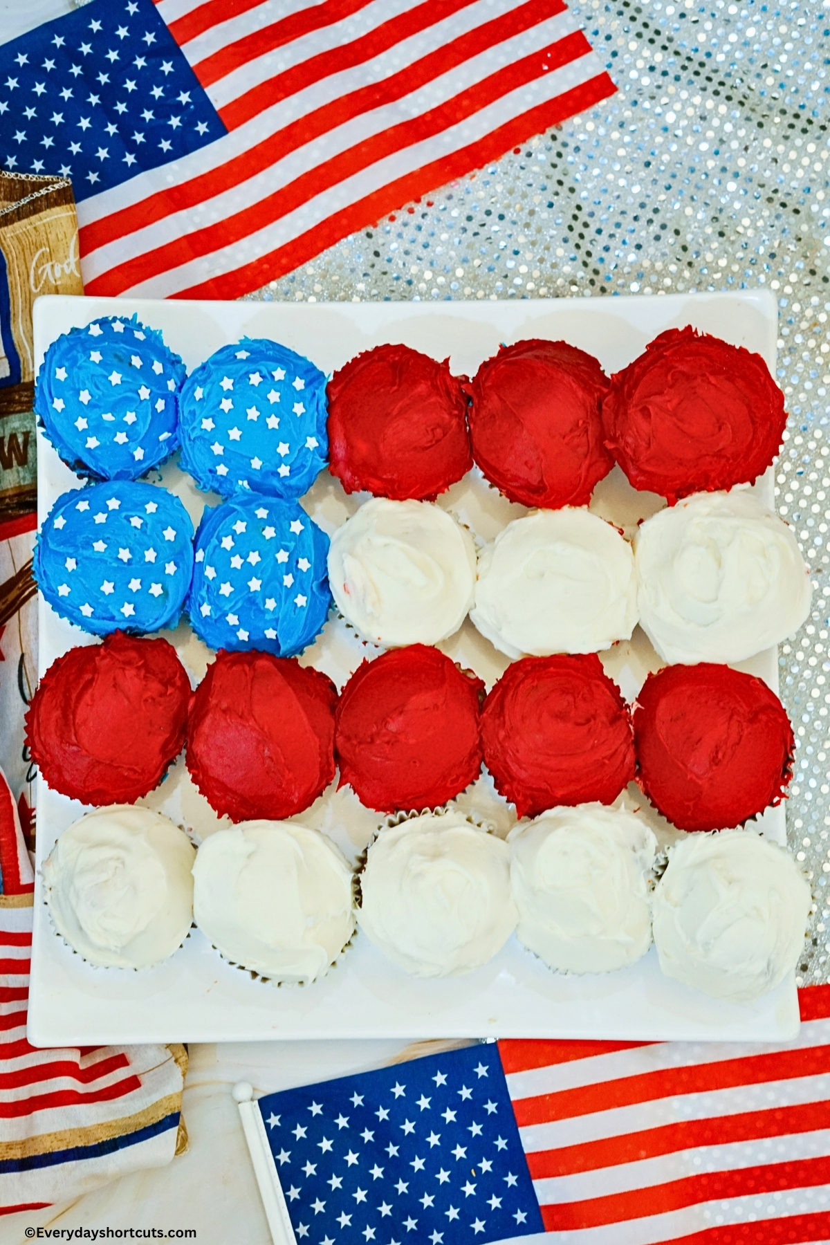 Cupcakes frosted in red white and blue and in the shape of American flag on white platter
