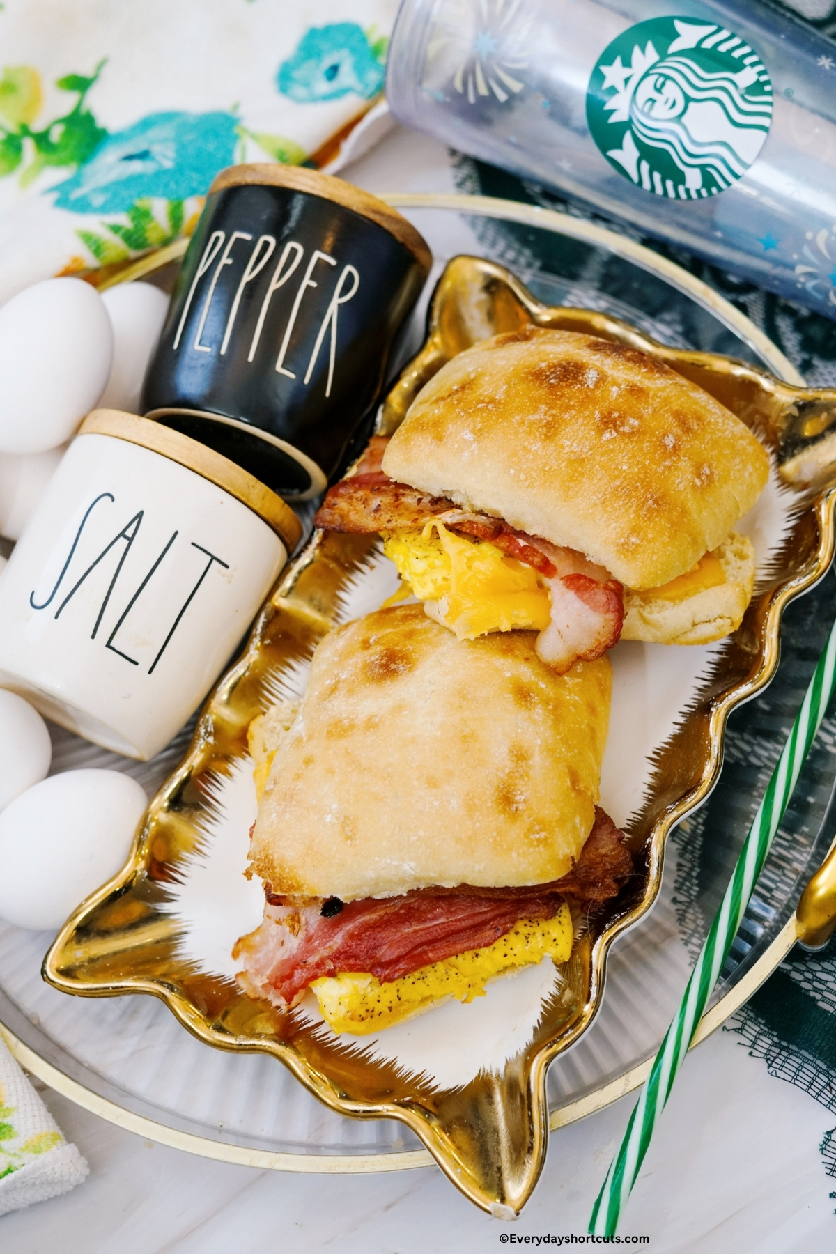 copycat Starbucks bacon gouda breakfast sandwiches on a platter next to salt and pepper shaker and Starbucks cup