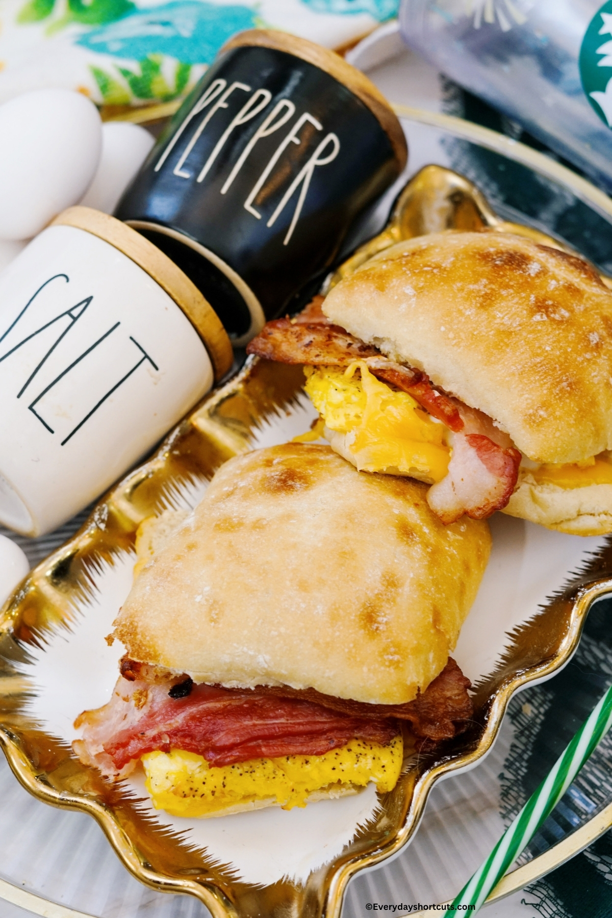 bacon gouda breakfast sandwiches on a platter next to salt and pepper shakers