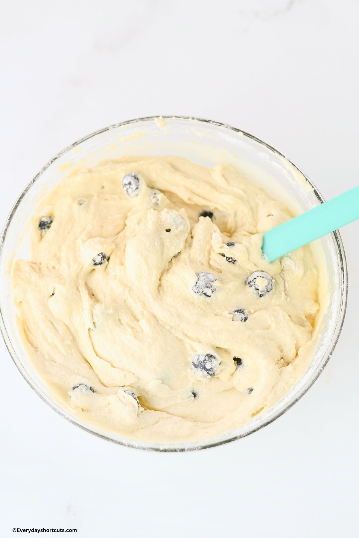 blueberries folded in cake batter in a bowl