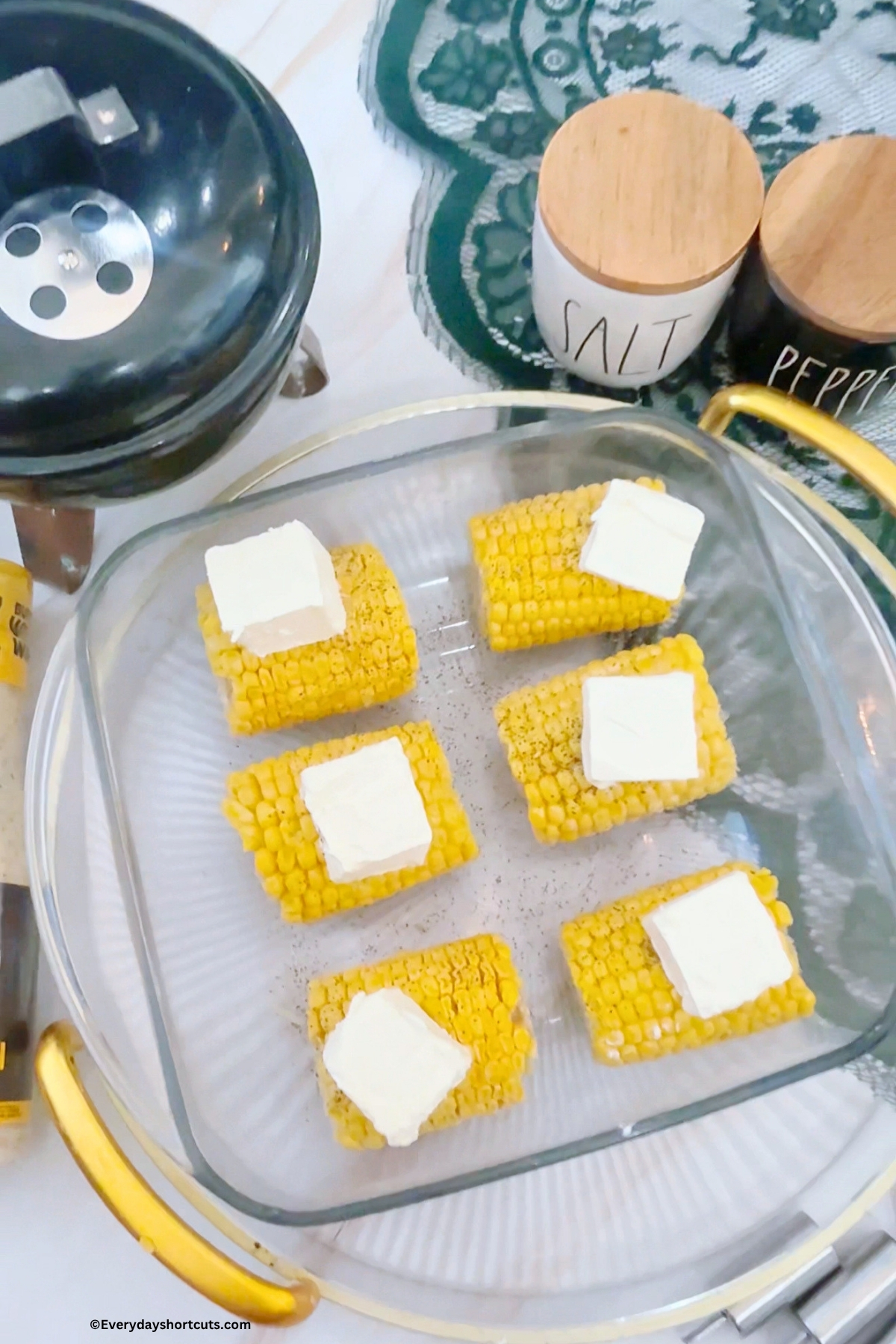 corncob in a baking dish with a slice of butter on top of each one