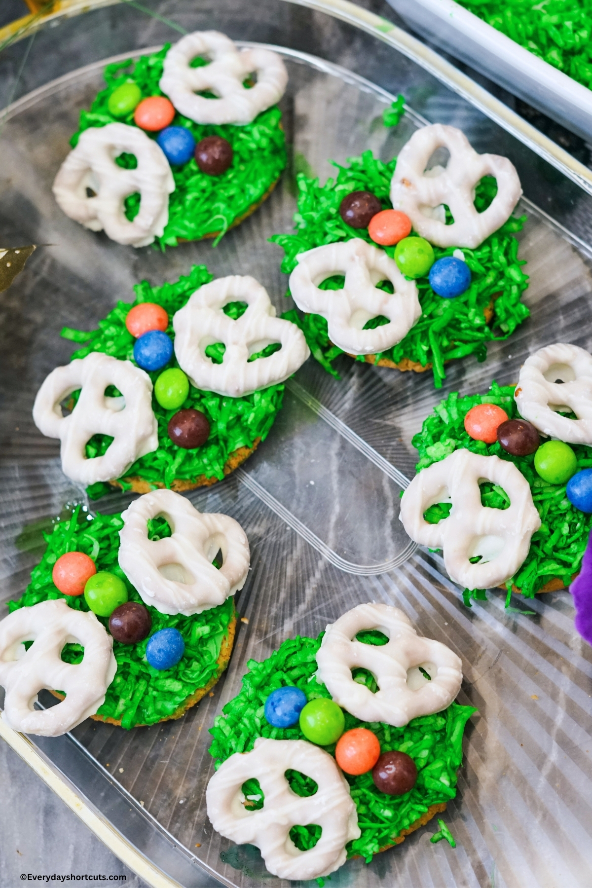 green frosted cookie with green shredded coconut and topped with skittles candies for the butterfly body and white pretzels for the butterfly wings