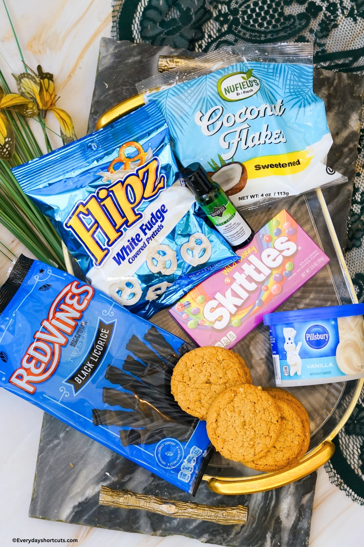 ingredients shown: coconut flakes, green food coloring, white pretzels, skittles, black licorice, sugar cookies, vanilla frosting