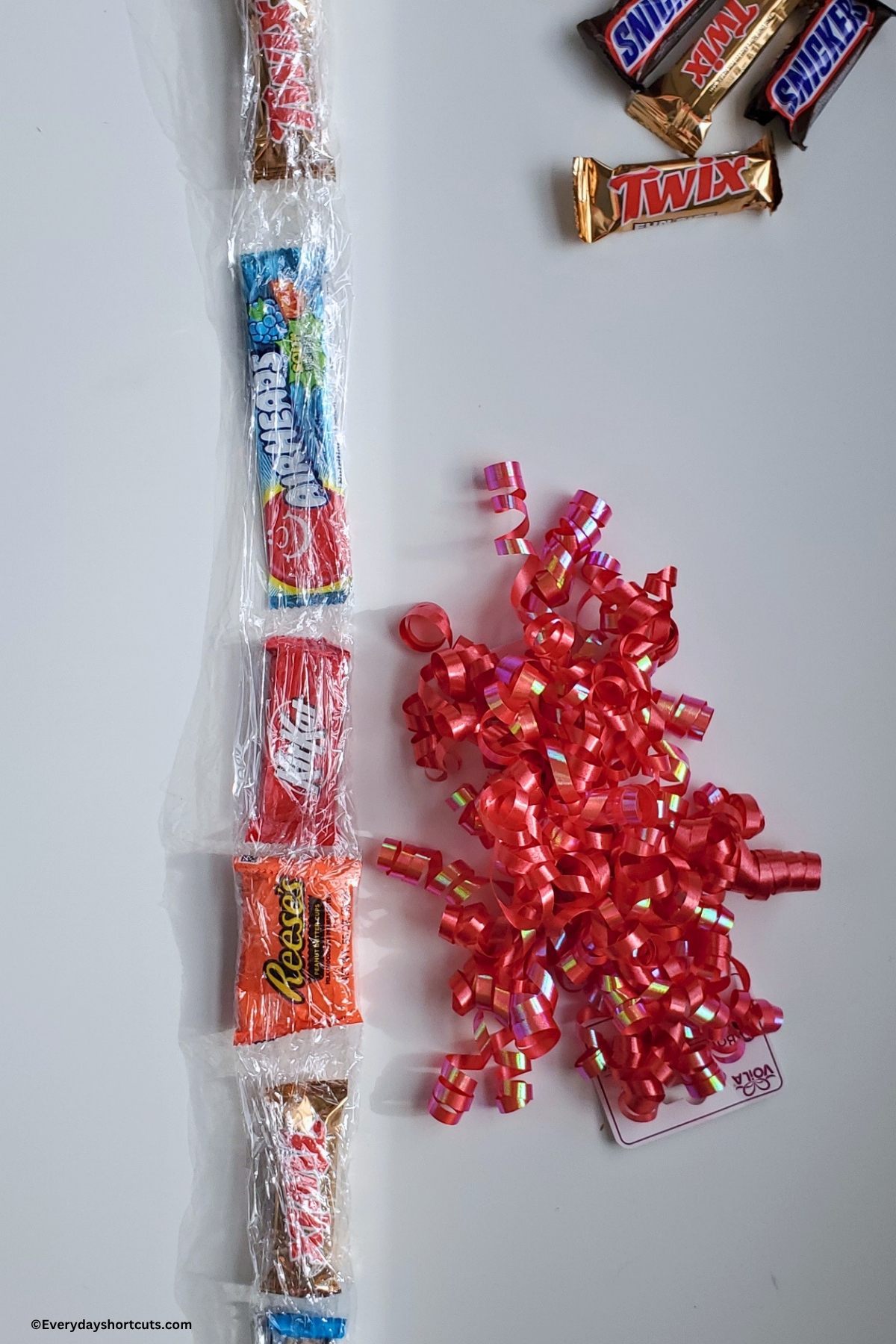 airhead and candy bars wrapped in a straight line next to curled red ribbon