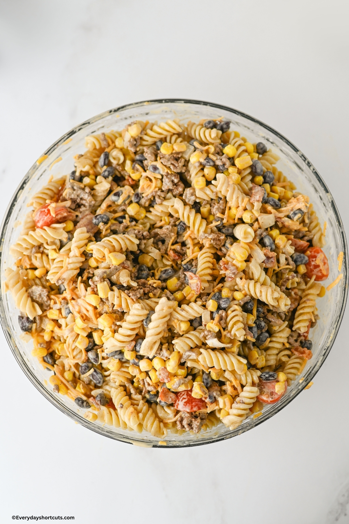 creamy tangy dressing mixed in with cowboy pasta salad in a bowl