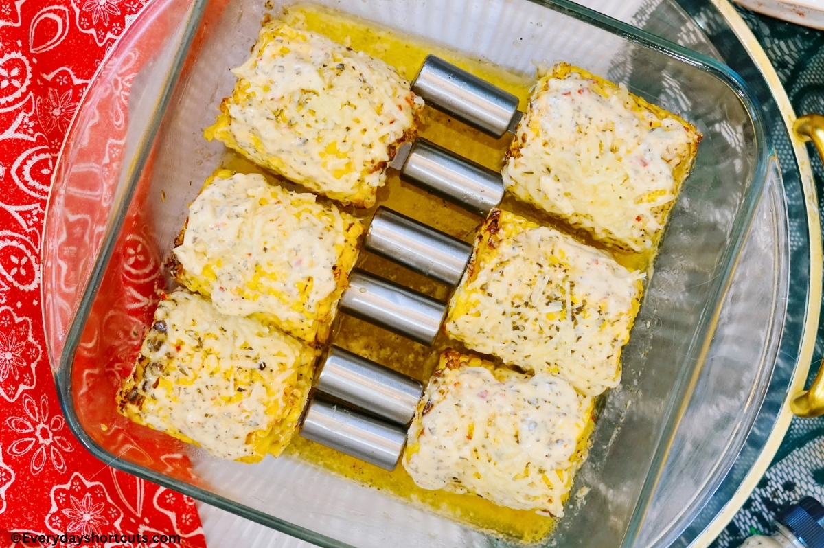 garlic parmesan corn on the cob in a baking dish next to a red napkin