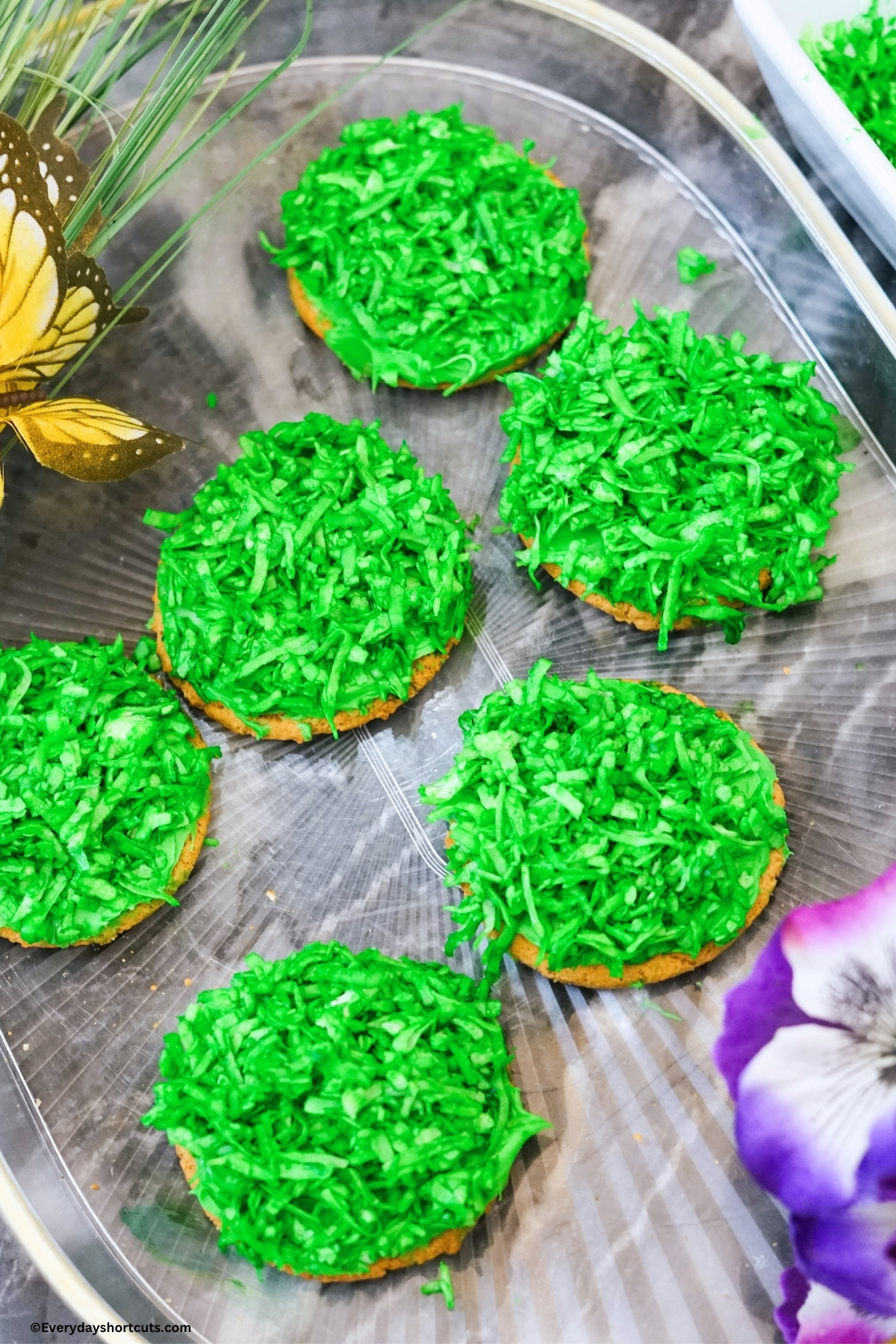 green dyed shredded coconut on top of green frosted cookie
