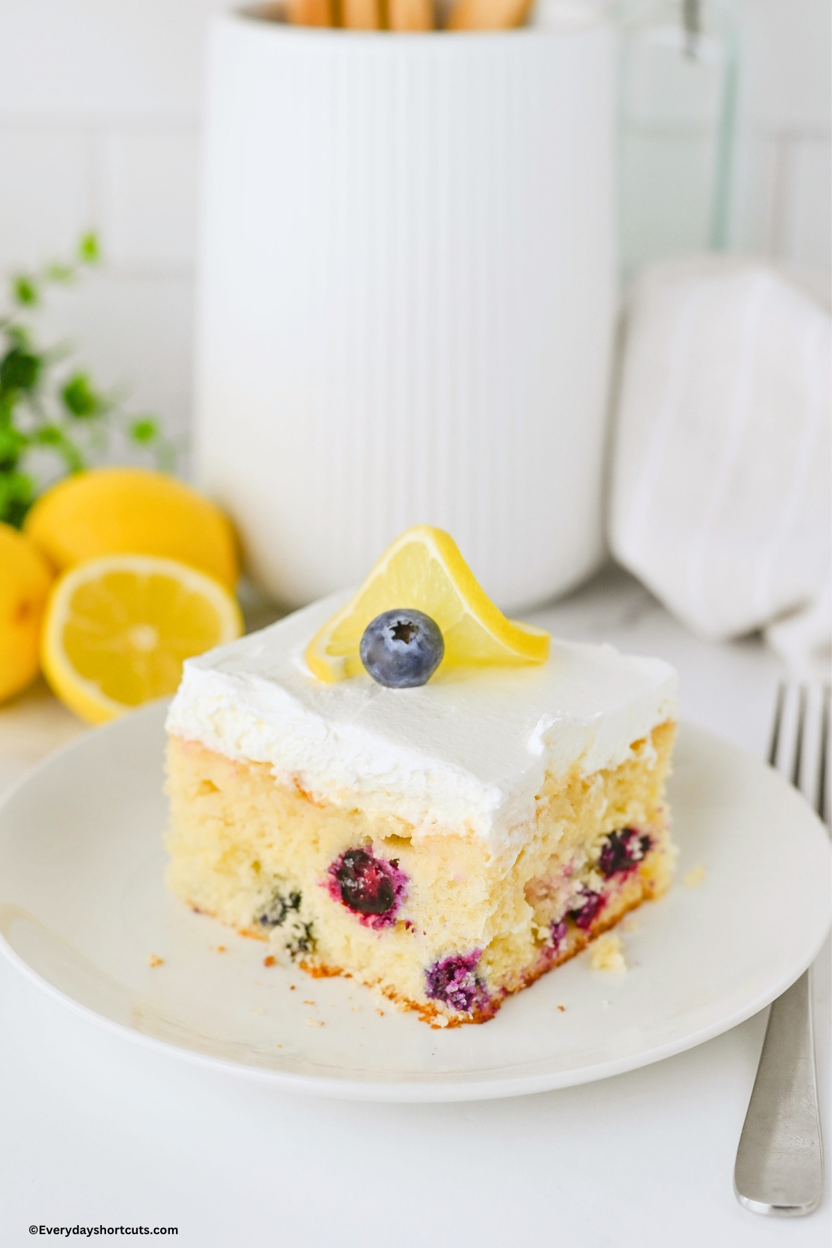 slice of lemon blueberry cake on a white plate next to a fork