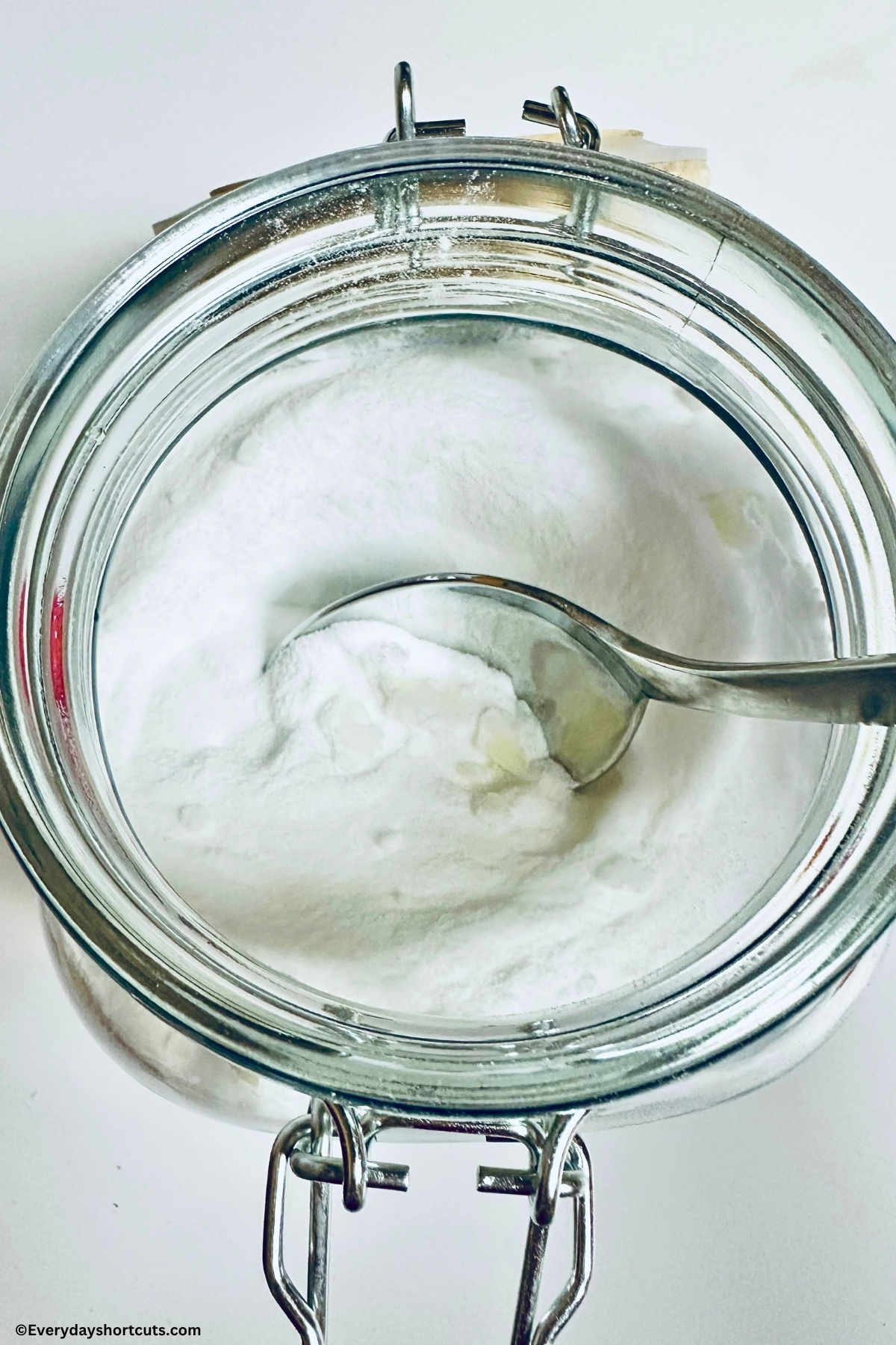 natural powder laundry detergent ingredients in a glass jar getting mixed by a spoon