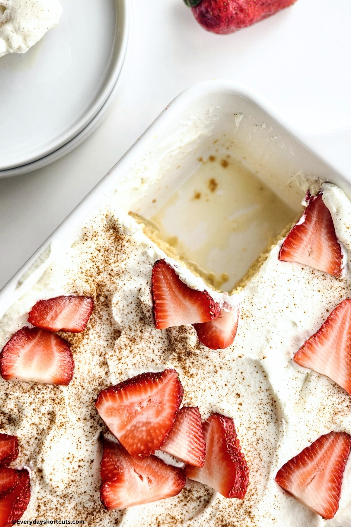 over top close up of tres leches cake in white baking dish with a slice taken out