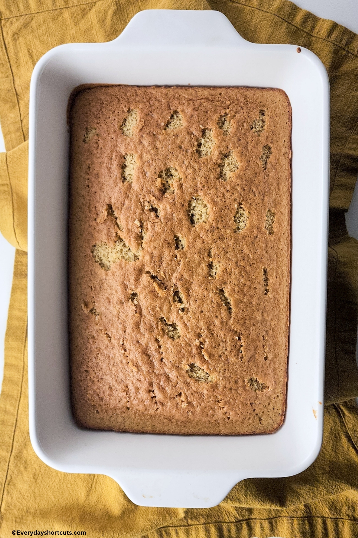 baked tres leches cake in a white baking dish on a yellow towl