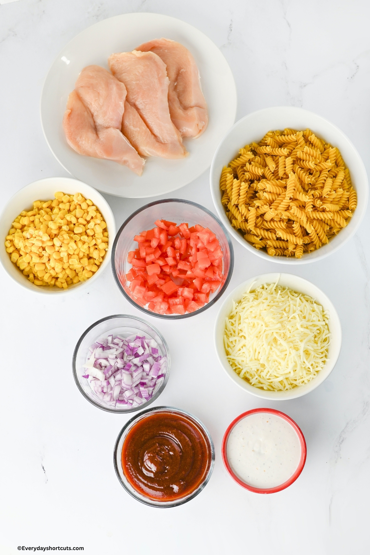 ingredients shown: chicken, pasta, corn, tomatoes, shredded Monterey jack cheese, red onions, BBQ sauce and ranch dressing