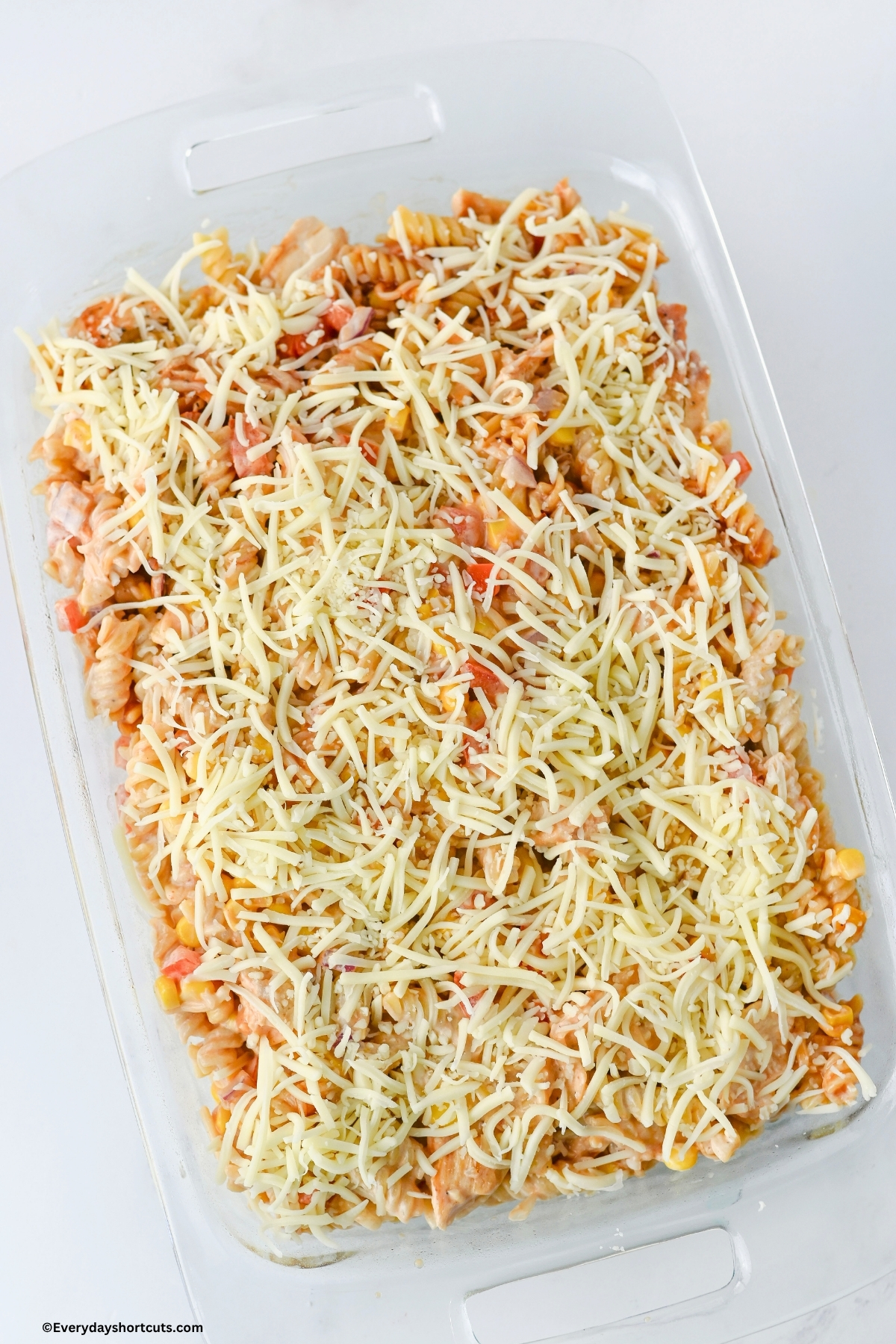 Chicken casserole in a baking dish with shredded Monterey Jack cheese on top