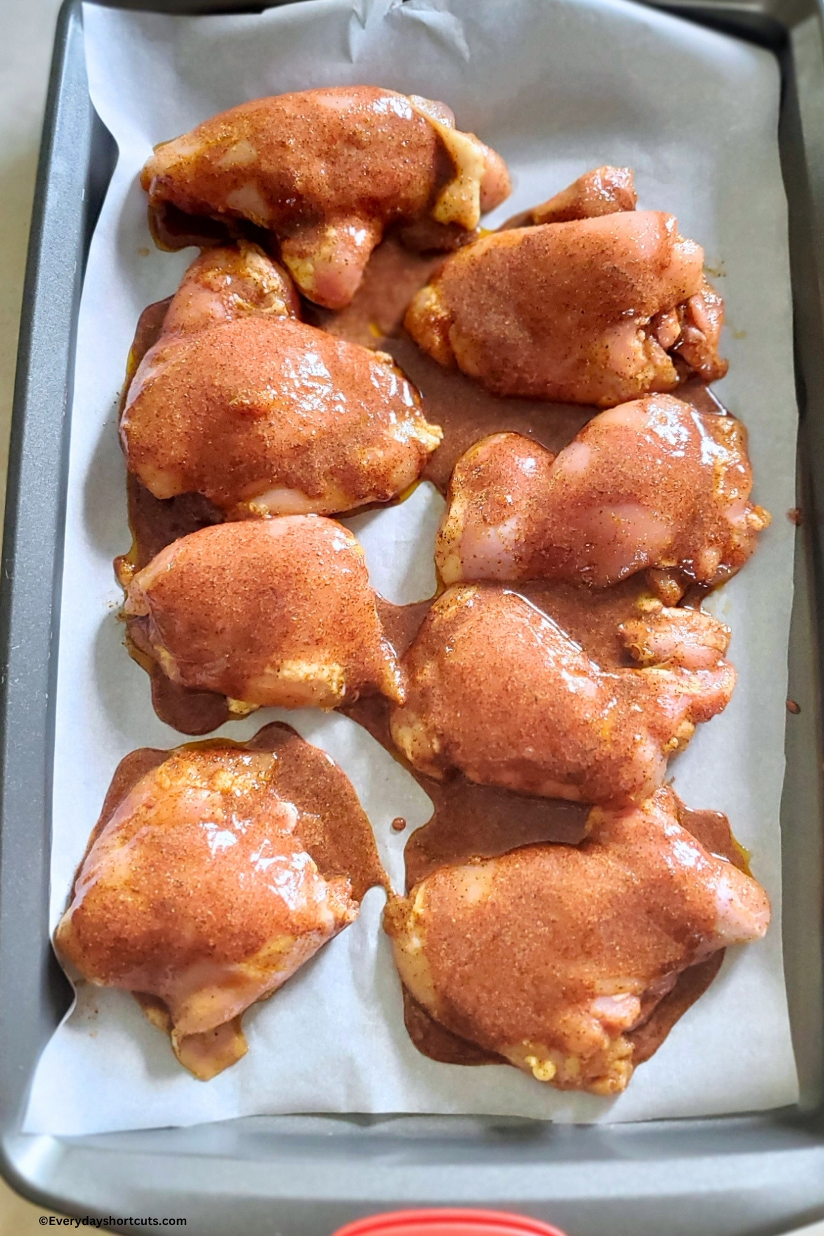 hot honey sauce coated on chicken thighs on a lined with parchment paper cookie sheet