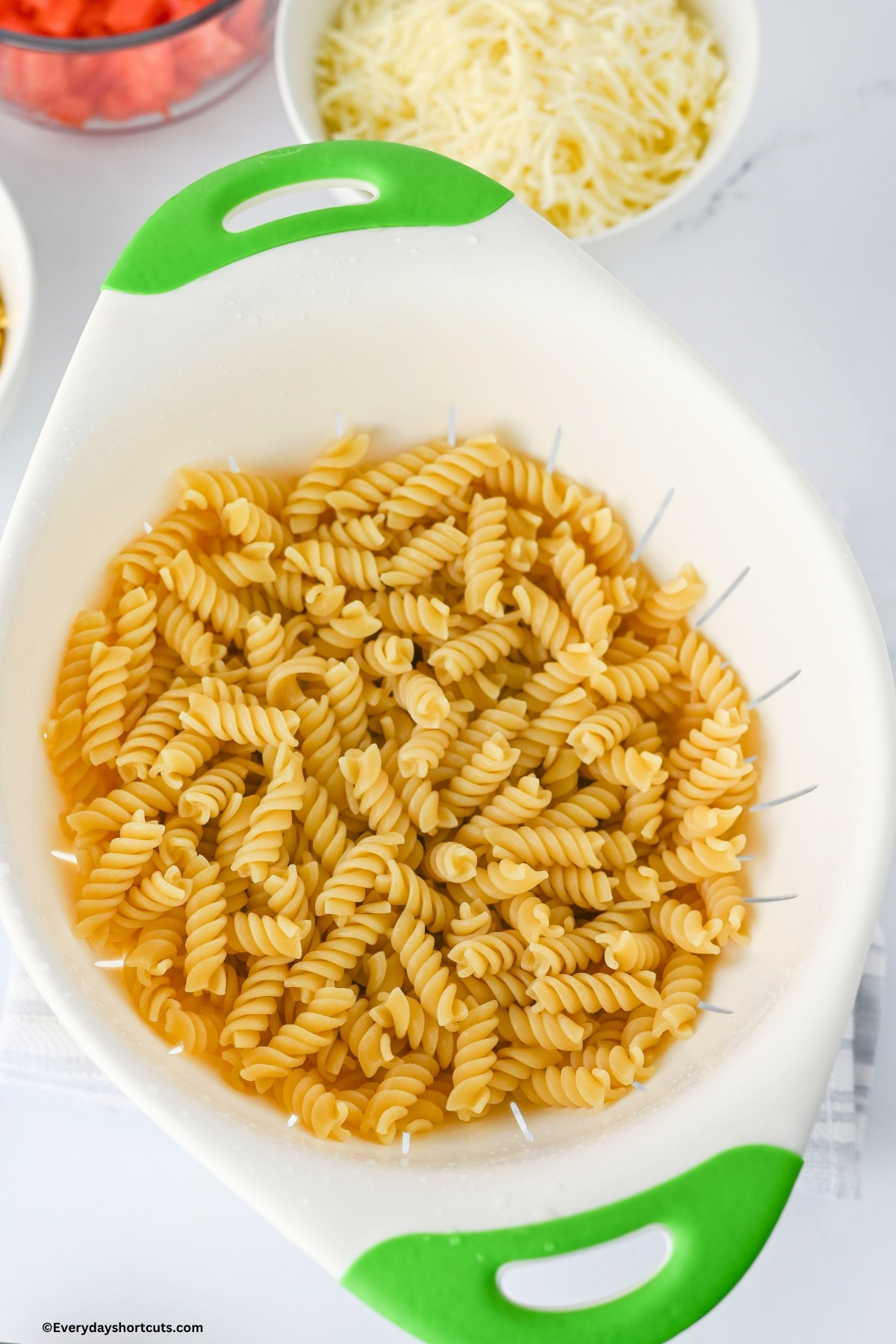cooked rotini pasta in a white and green strainer