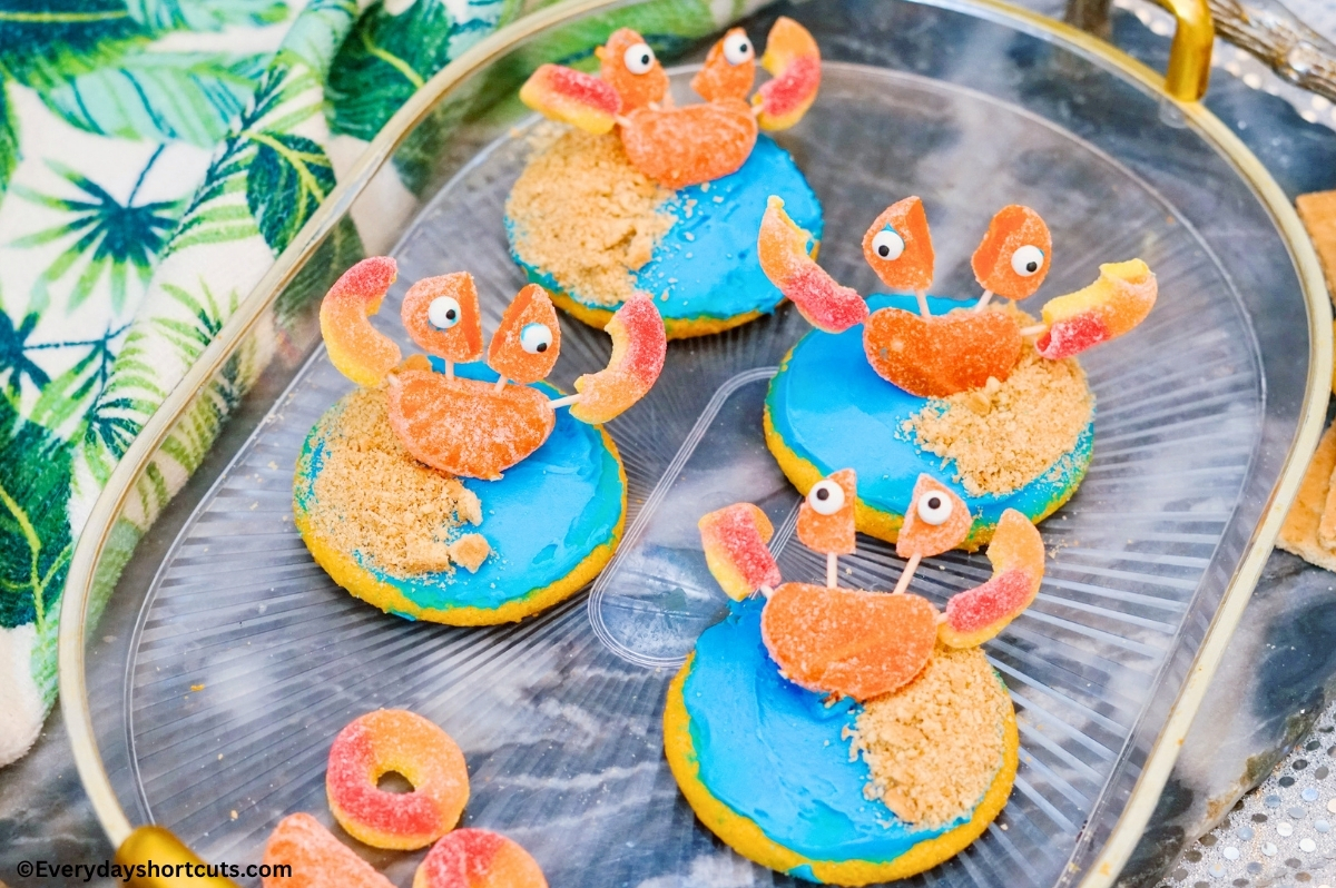 beach crab cookies on a clear and gold platter next to a palm trees kitchen towel