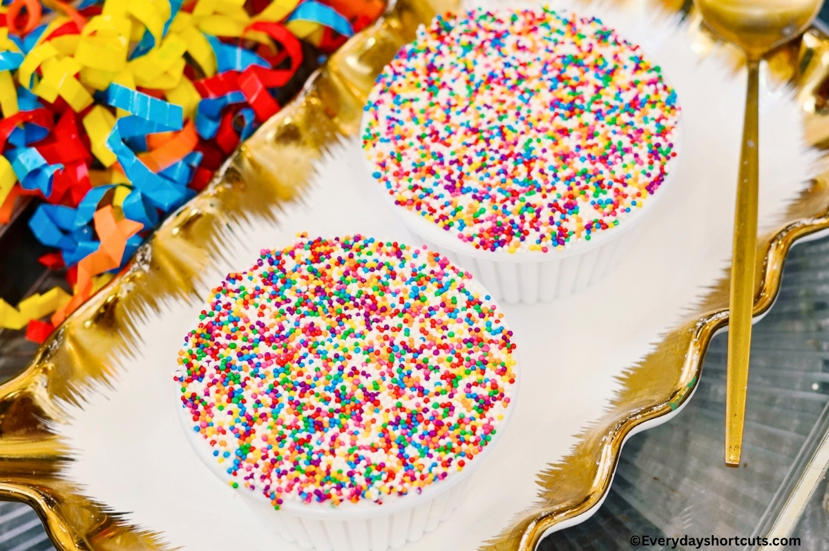 dot cakes on a gold and white platter next to a spoon and curled ribbon