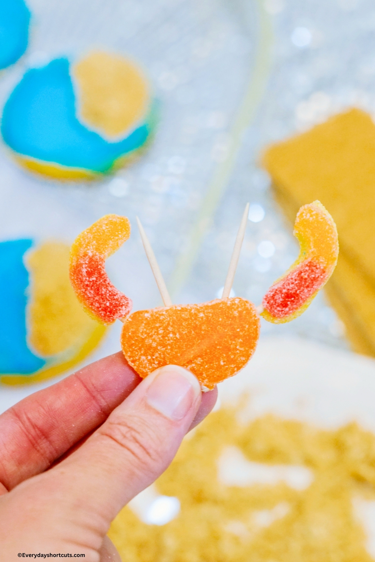 holding an orange slice with 2 cut peach rings on each side and 2 toothpicks in the middle