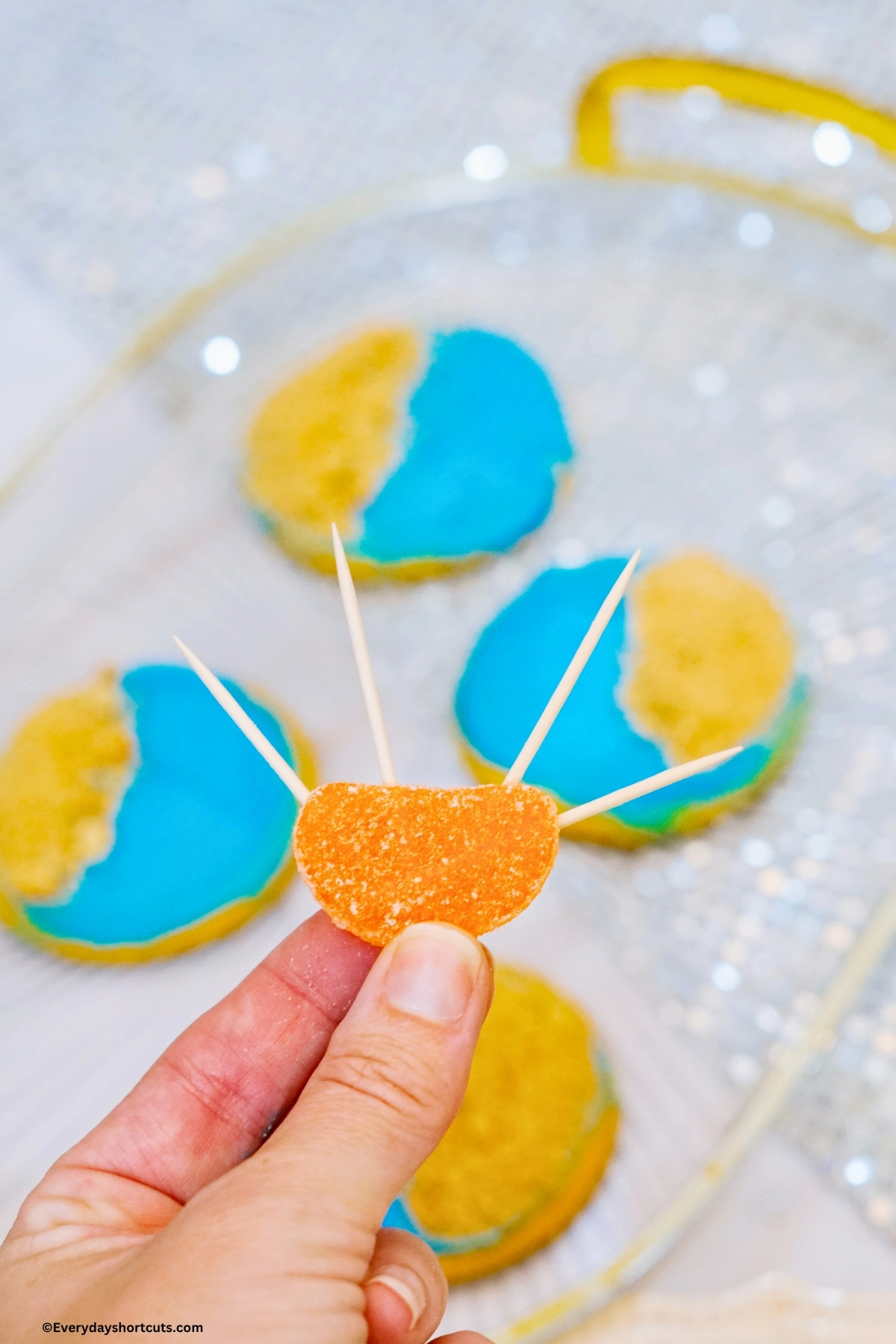 holding an orange slice with 4 toothpicks sticking out the top