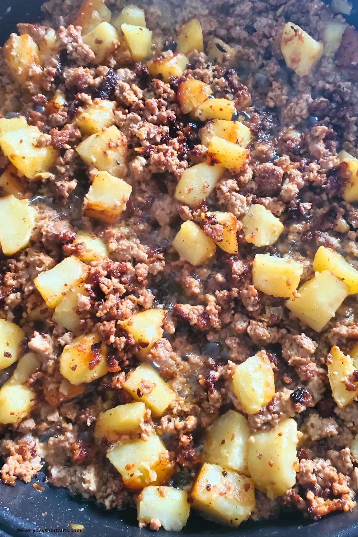 browned ground beef with cooked potatoes in skillet