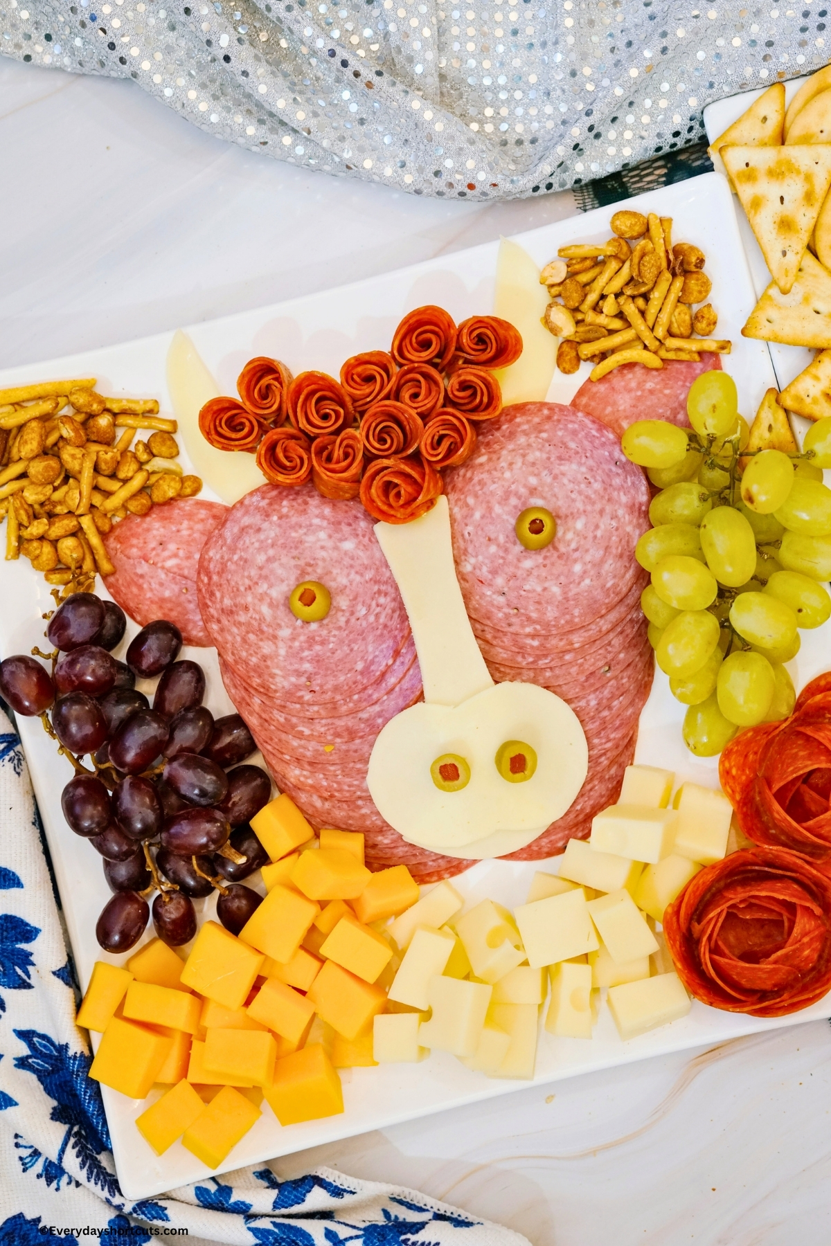 highland cow charcuterie board filled with salami, pepperoni, cheeses, grapes and nuts