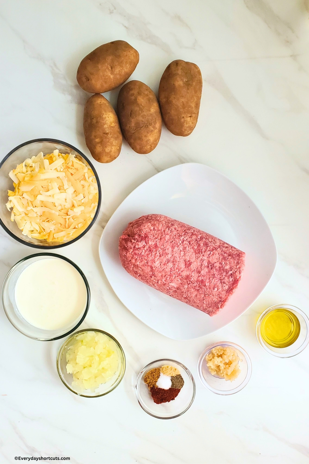 ingredients shown: russet potatoes, shredded cheese, ground beef, heavy cream, onions, olive oil, minced garlic, salt, pepper, onion powder, cumin, paprika