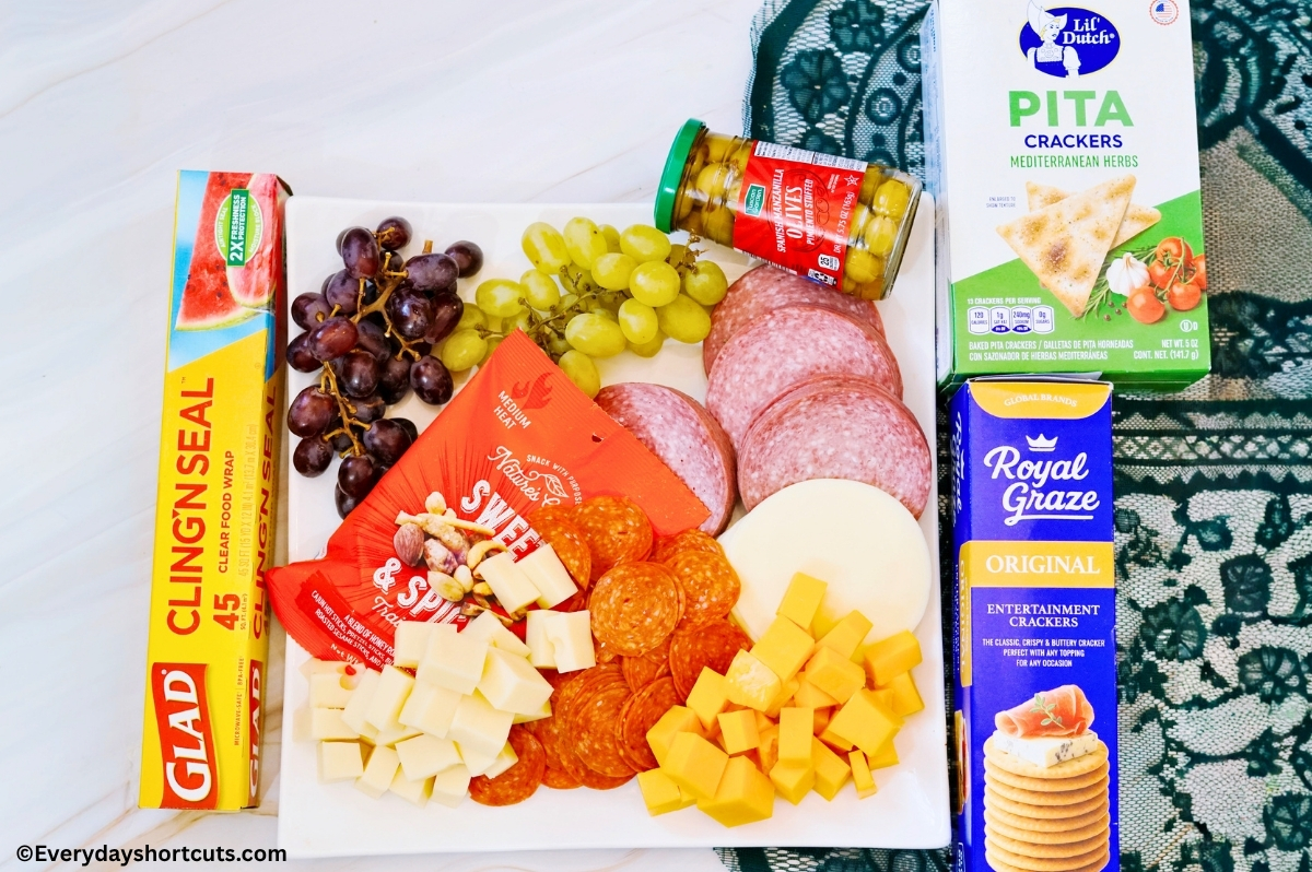 ingredients shown: crackers, green olives, cubed cheeses, nuts, provolone cheese slices, salami, pepperoni, grapes
