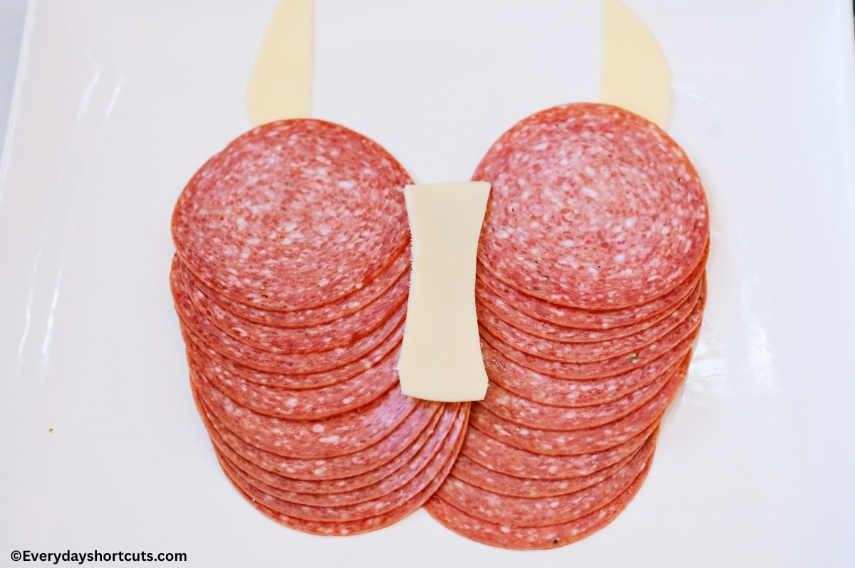 2 rows of overlapping salami next to each other, provolone cheese strip for nose and horns