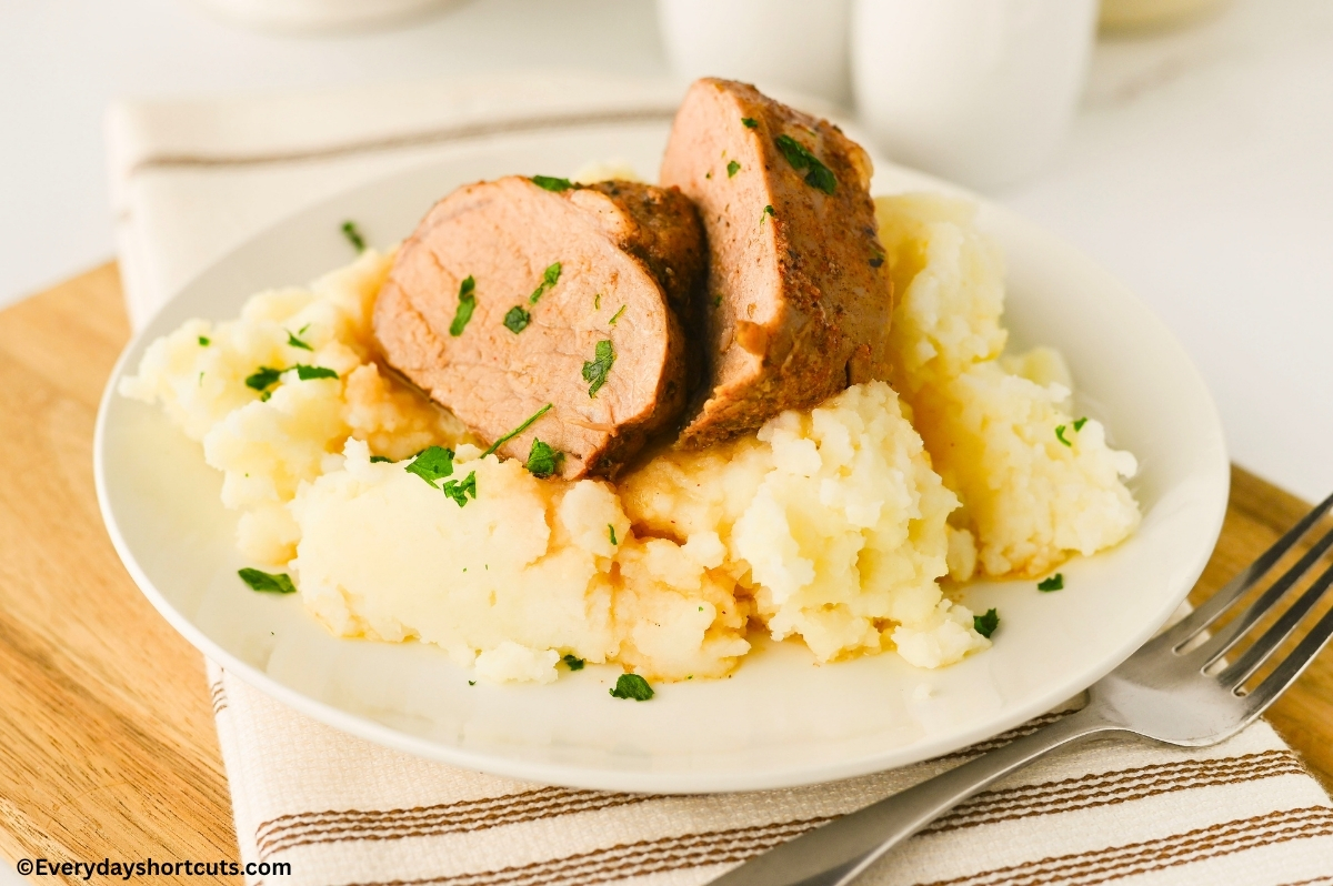sliced pork tenderloin on a plate with mashed potatoes