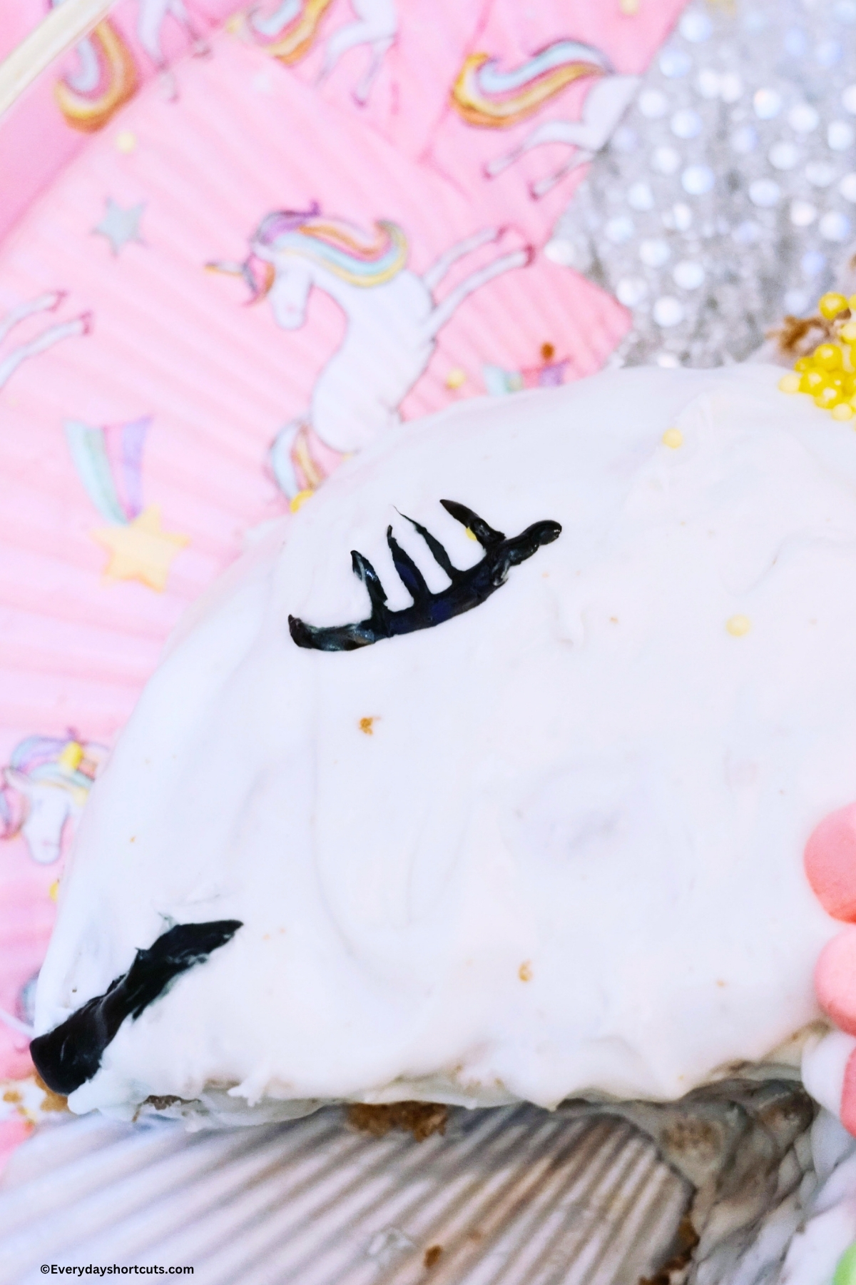 eyelashes and mouth drawn on a cake with black decorating gel