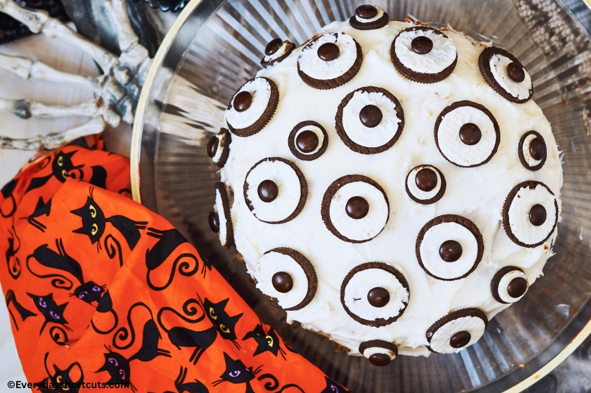 cake with white frosting with Oreo and M&M's to look like eyeballs next to a black cat napkin