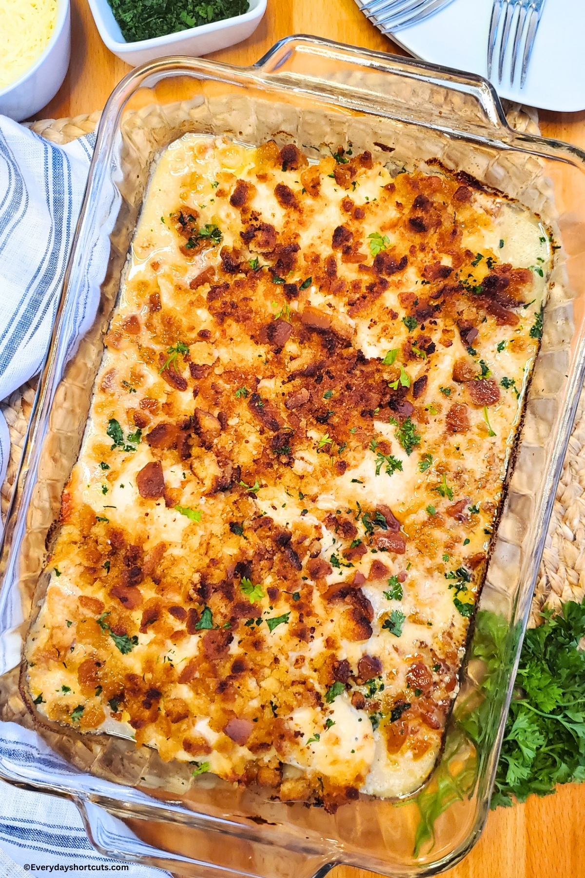 Baked Caesar Chicken in a casserole dish next to a blue and white striped napkin