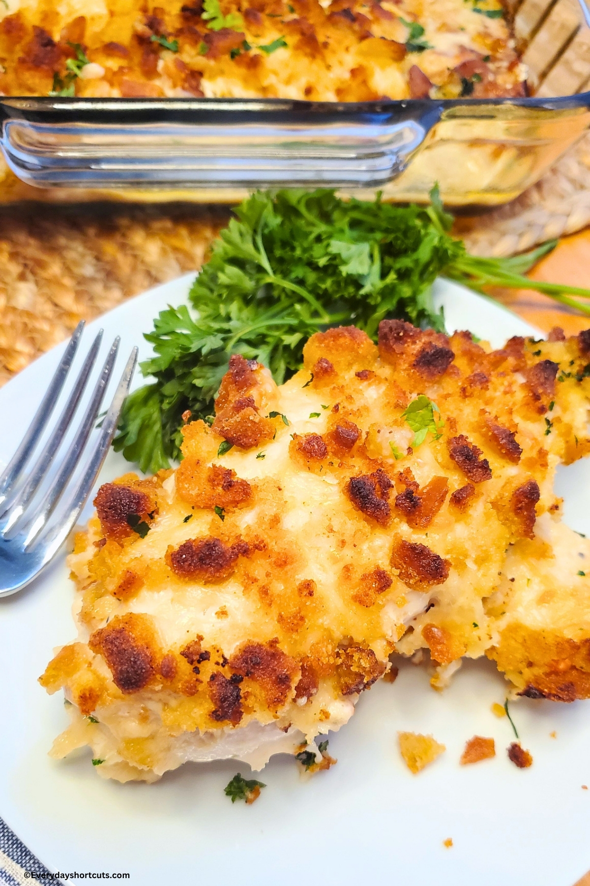 Caesar chicken on a white plate next to a fork and parsley