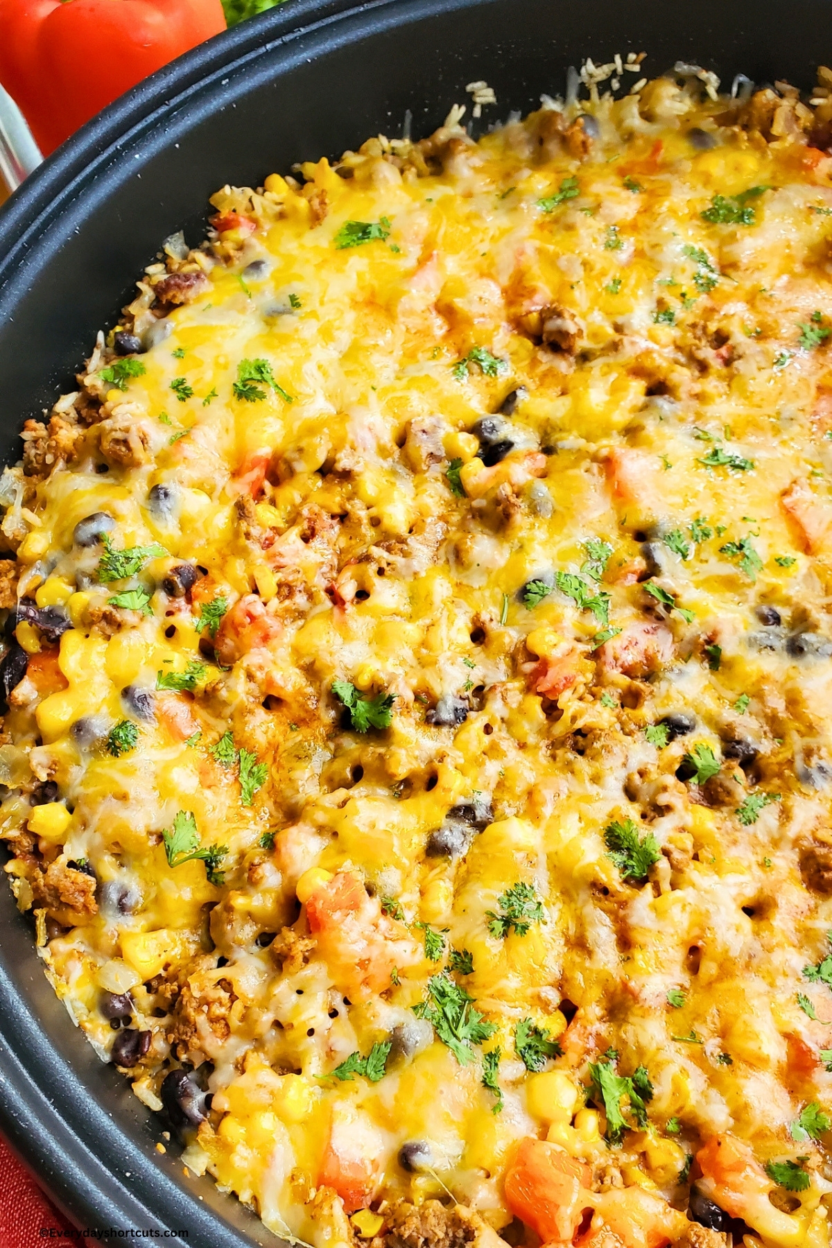 Mexican beef and rice skillet topped with melted cheese and parsley garnish in a skillet