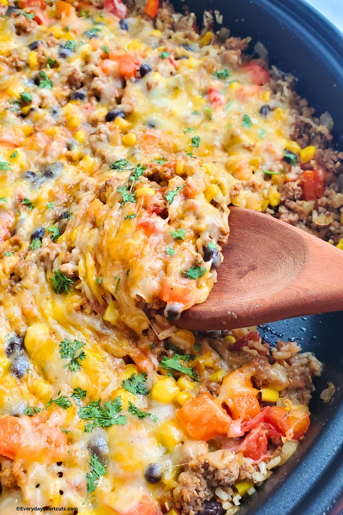wooden spoon inside skillet with Mexican beef and rice meal