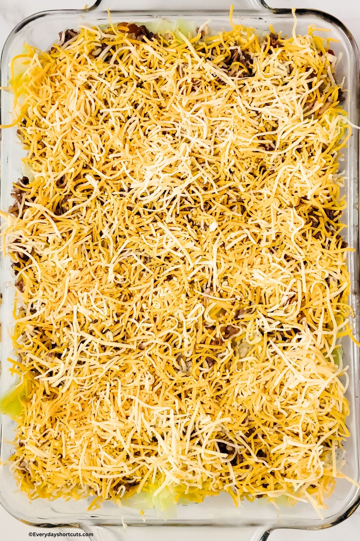 unstuffed cabbage roll in a baking dish with shredded cheese on top