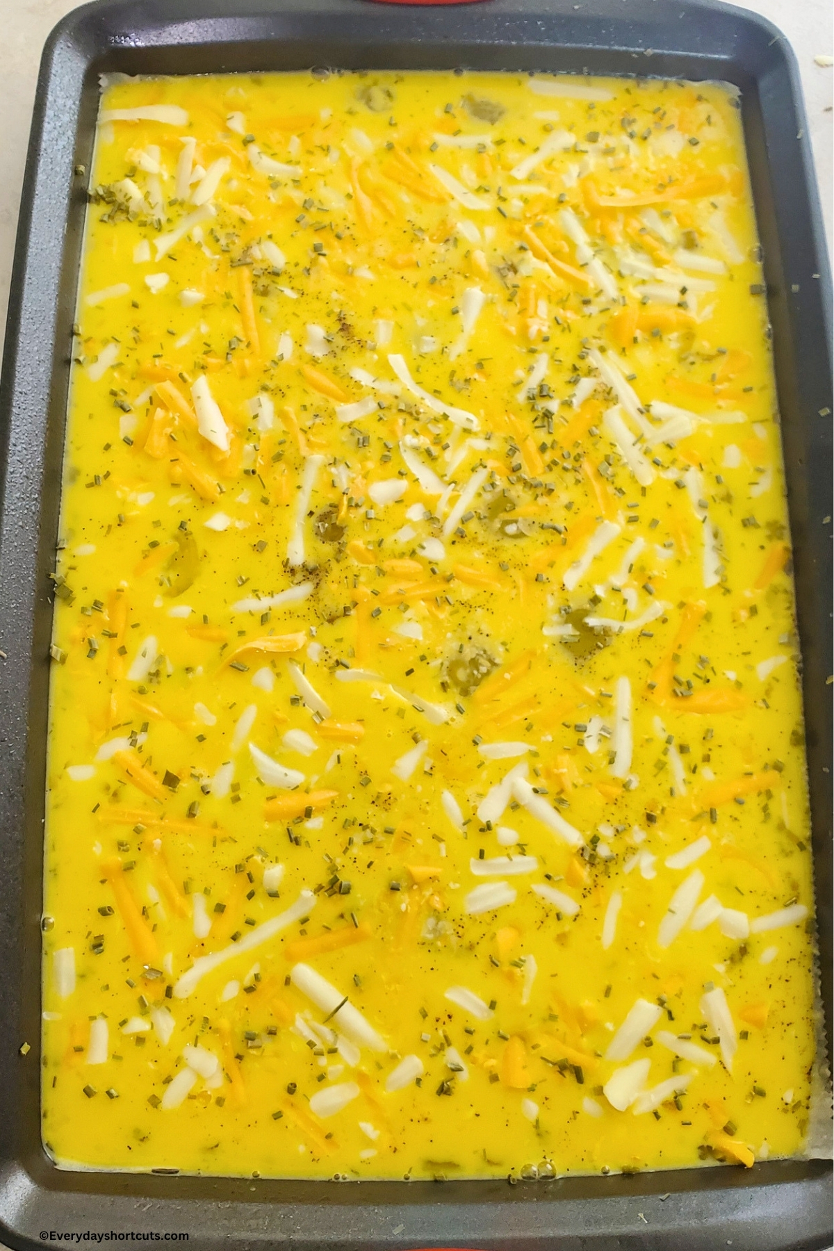 scrambled eggs with chives, salt, pepper and shredded cheese on a baking sheet before baking