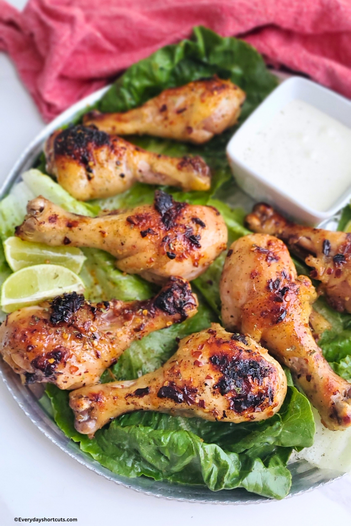 firecracker chicken on a bed of lettuce on a sliver platter next to a red napkin