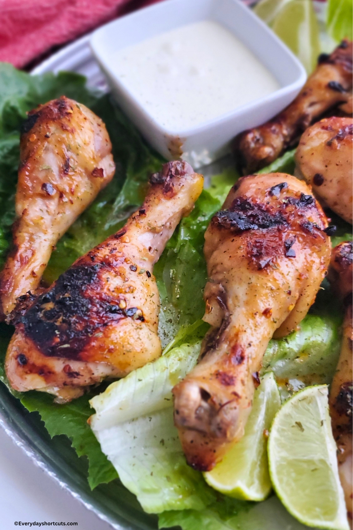 up close of firecracker chicken on a bed of lettuce next to sliced limes