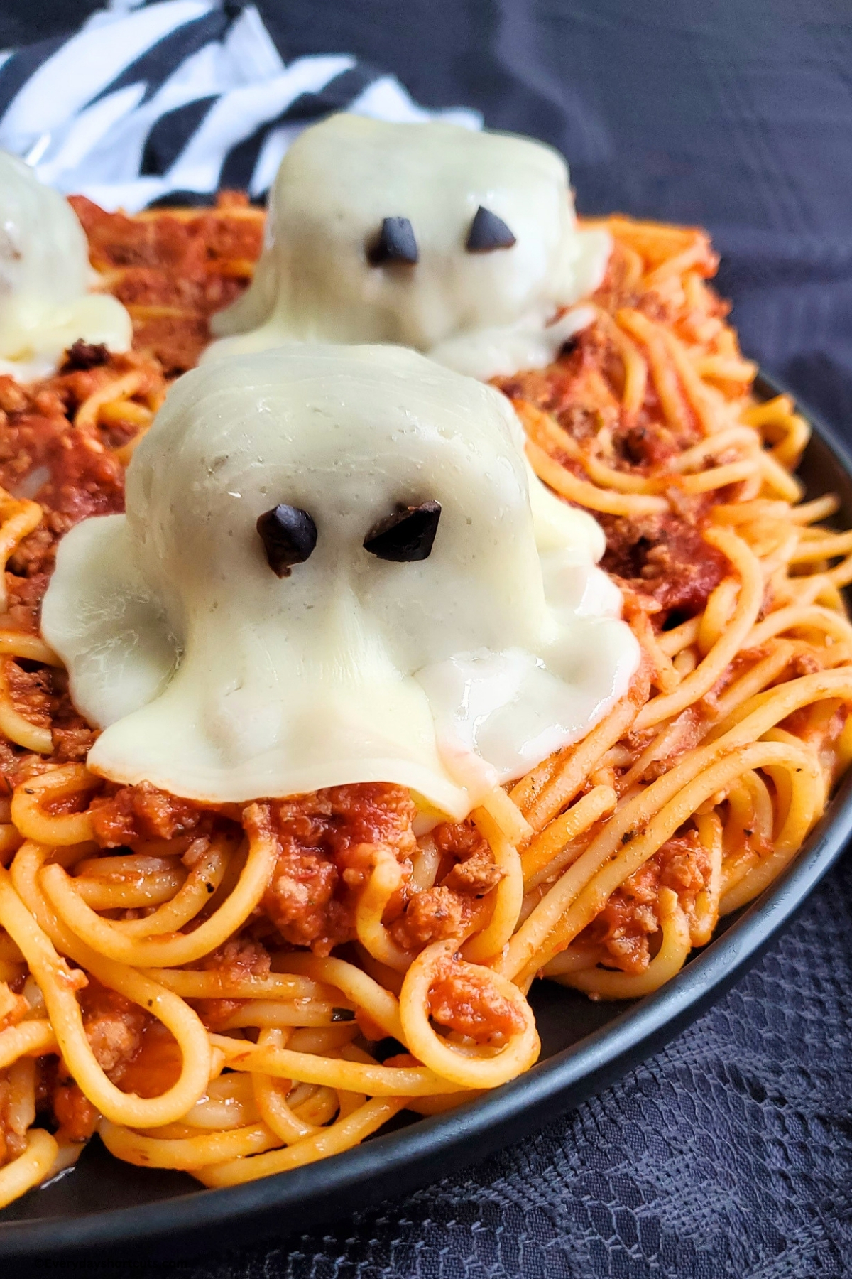 meatballs with melted cheese and olive eyes to look like ghosts on top of spaghetti