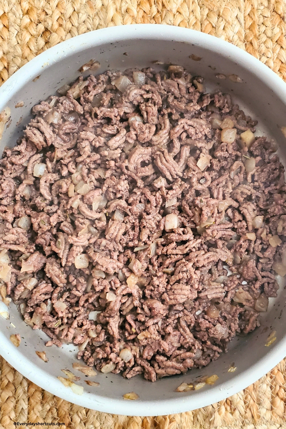 browned ground beef in a pan with onions and garlic