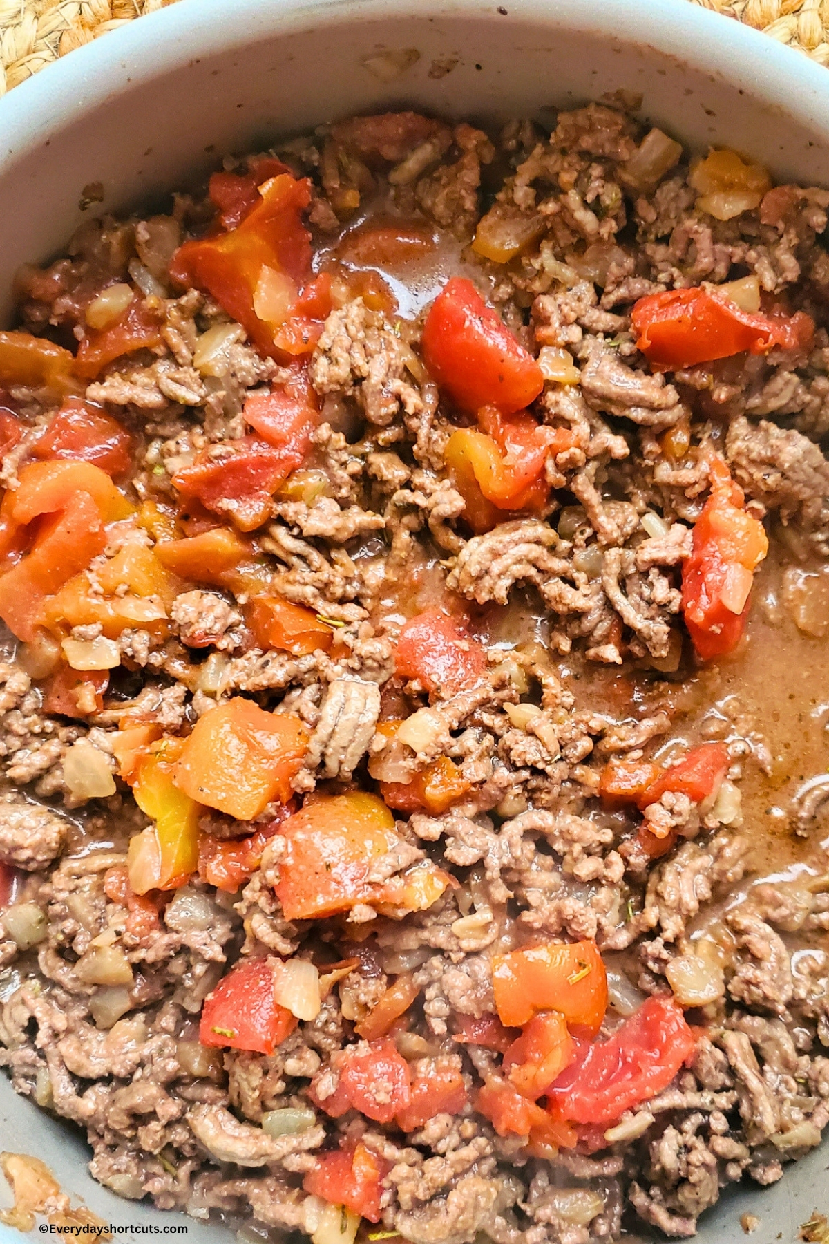 browned ground beef in a pan with diced tomatoes