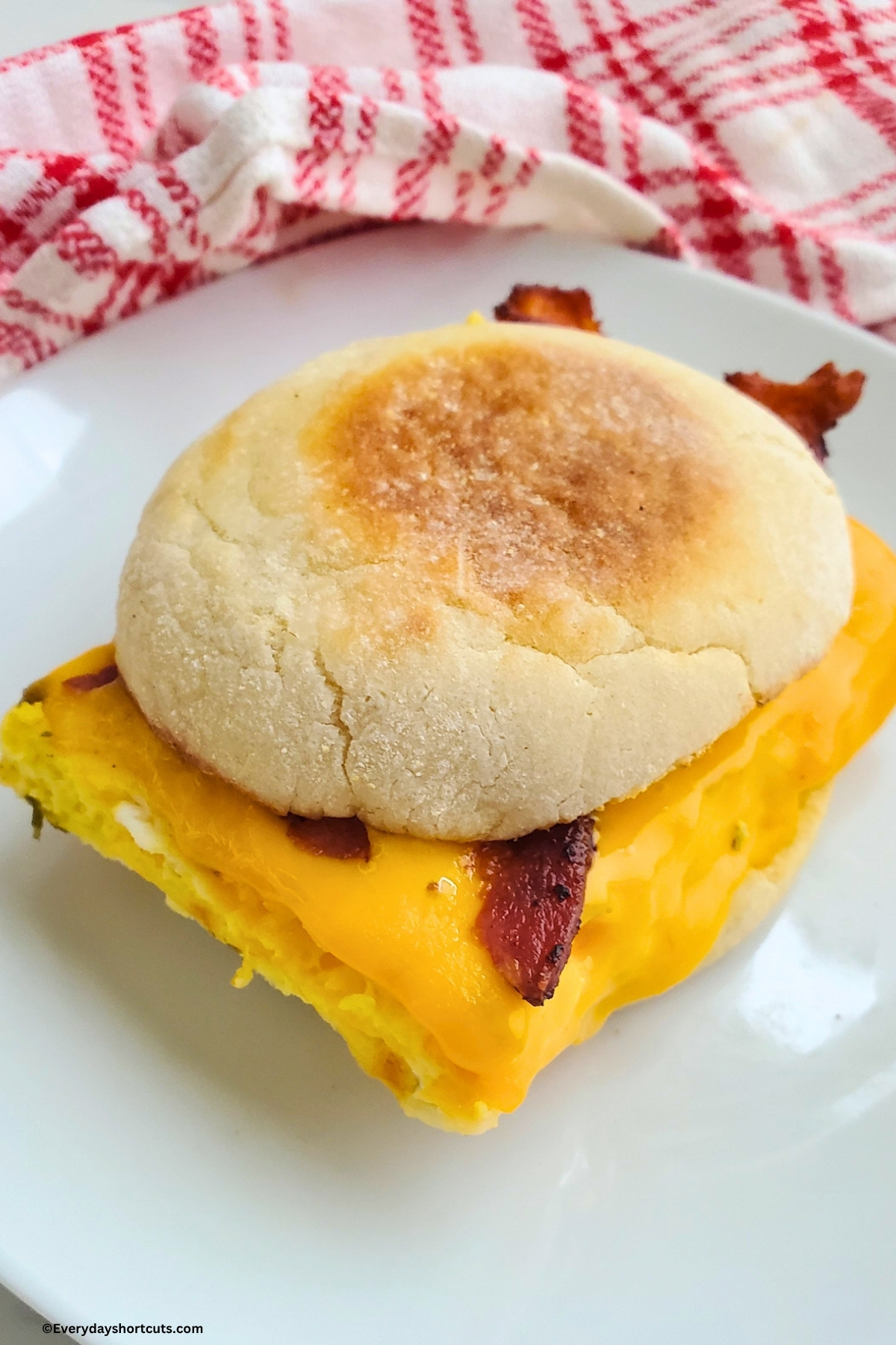 breakfast sandwich made with an English muffin, egg patty, bacon and cheese